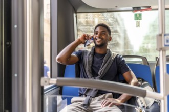 African casual businessman on the way to work sitting on the bus talking to the mobile