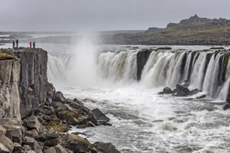 People standing in front of a waterfall at a river, cascades, spray, rapids, summer, foggy,