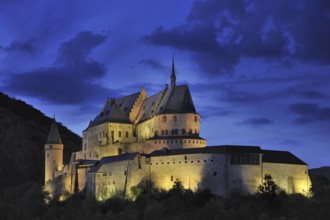 The fortified Vianden Castle illuminated at night in Luxembourg