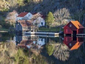 Fjord near Ana Sira at the norwegian southern coast, lonely houses at the foot of a rock formation,