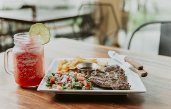 Skirt steak nicaraguan with salad and drink strawberry lemonade served on wooden table. Delicious