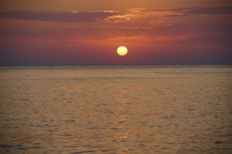Sunset over the calm sea under an orange sky, Mandraki, Nisyros, Dodecanese, Greek Islands, Greece,