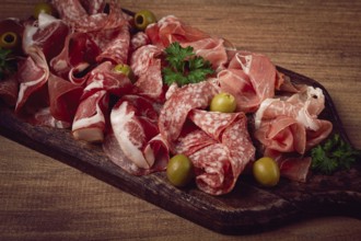 Assortment, sliced meat appetizer, prosciutto, salami and ham, with olives, on a wooden board,