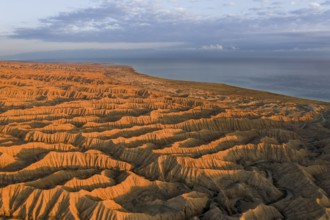Landscape of eroded hills, badlands at sunset, Lake Issyk Kul in the background, aerial view,