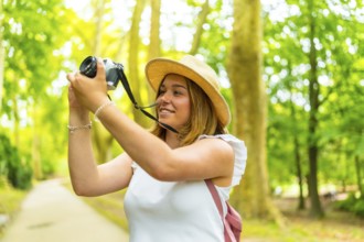 Young female photographer making photos in nature standing in the middle of footpath among green