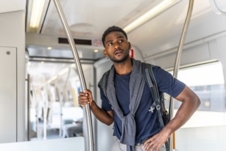 African young man travelling by public transportation standing on an intercity train
