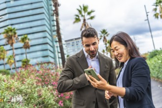 Multi-ethnic business coworkers using phone and smiling standing in a tropical modern city