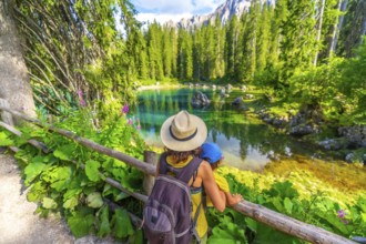 Mother and child enjoying breathtaking view of lake carezza's turquoise waters, surrounded by lush