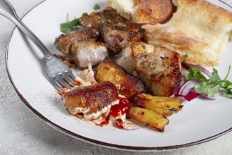 A plate with leftover pork kebab, with bread, on a white plate, close-up, there are no people
