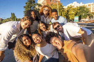 Frontal view of multi-ethnic group of happy friends taking selfie together in the street