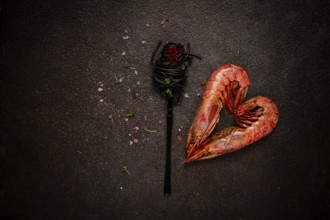 Black spaghetti, wrapped on a fork, langoustines in the shape of a heart, on the table, dish