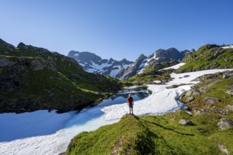 Mountaineer in front of lake with snow remains, Landscape at the mountain hut Trollfjord Hytta,