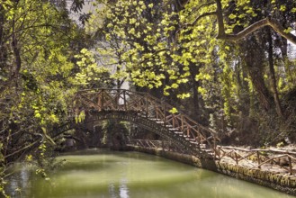 Wooden bridge over a quiet pond in the middle of a green forest, Rodini Park, City Park, Rhodes