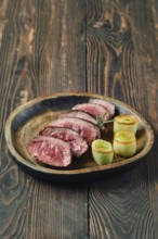 Tender roasted beef slices arranged on a wooden plate, accompanied by artfully presented
