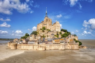 Majestic abbey on a mountain in a vast landscape under a partly cloudy sky, Le Mont-Saint-Michel