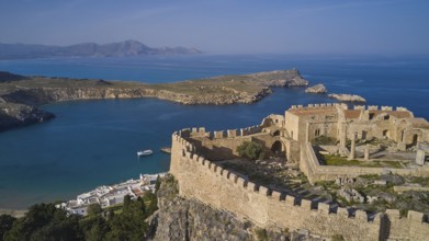 Drone shot, Acropolis of Lindos, Late afternoon light, Ancient fortress on a headland above a blue