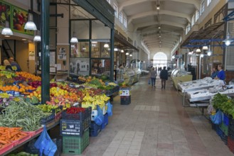 A market hall with various colourful fruit and vegetable stalls and people shopping, Xanthi,