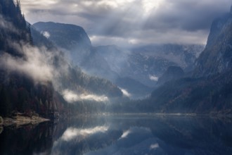 The Vordere Gosausee in autumn. The Dachstein in clouds. Rays of sunshine shine through the clouds.