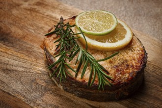 Salmon steak, fried, on a cutting board, top view, rosemary, lemon and lime, homemade, one serving,