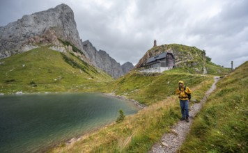 Mountaineer on hiking trail at Wolayersee, Alpine Club hut Wolayerseehütte, rocky cloudy mountains,