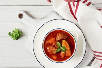 Potatoes stewed with meat, in tomato sauce, with spices and herbs, no people, on a white table