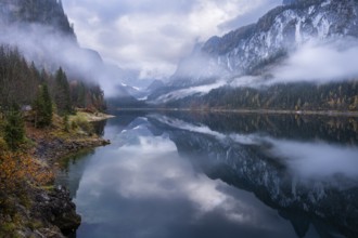 The Vordere Gosausee in autumn with a view of the Gosaukamm on the right. The Dachstein in clouds