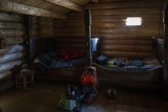 Rustic interior of a wooden hut with small beds and a rucksack, Olavsweg or Olavsleden, backdrop