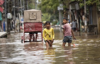 Children wade through a flooded street after heavy rains in Guwahati, India on April 28, 2025