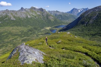 View of mountain landscape and valley with lakes, mountaineer on hiking trail to the summit of