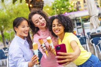 Three diverse female friends taking selfie enjoying an ice cream during holidays
