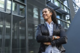 Female Latin entrepreneur smiling proud standing with arms crossed outside a block office