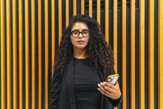 Portrait of a latin young businesswoman wearing eyeglasses and formal elegant black cltohes in a