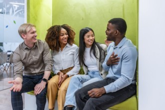 Four diverse colleagues enjoying a friendly conversation in a vibrant coworking space, fostering