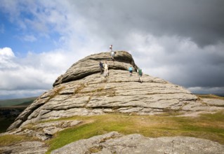 People scrambling on a granite tor near Haytor, Dartmoor national park, Devon, England, United