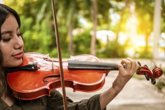 Close up of a girl with her violin playing a melody outdoors, Concept of smiling female violinist.