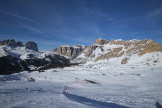 View of a ski resort piste with people skiing in Dolomites in Italy. Ski area Belvedere. Canazei,