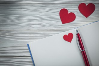 Red hearts ballpoint pen notebook on wooden board education concept