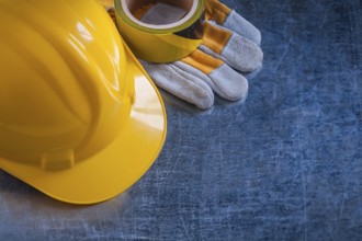 Safety tape yellow building helmet and protective gloves on scratched vintage metallic background