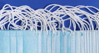 Close-up view of virus protection face mask with rubber ear straps on blue background as protection