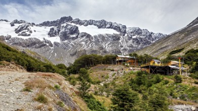Mountain landscape with snow-covered peak and huts in the foreground on a cloudy day, The landscape