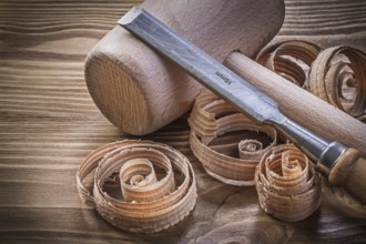 Wooden mallet flat chisels planning chips on vintage wood board construction concept