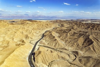 Desert on the shores of the Dead Sea. Asphalt highway meanders among the hills. Dead Sea mud has