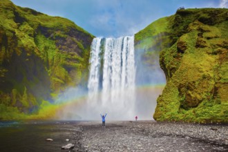 Grand waterfall in Iceland - Skogafoss. Picturesque huge rainbow appears in the water mist.