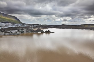 Skaftafell National Park. Ice covered with volcanic ash. Mirror Lake, formed as a result of thawing