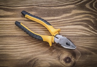 Gripping tongs on vintage wooden board construction concept