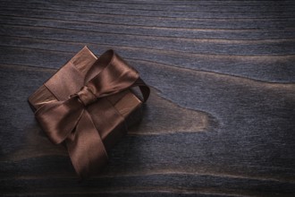 Boxed present with brown bows on vintage wood board