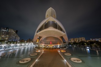 Futuristic architecture at night with illuminated structures reflecting on water in an urban