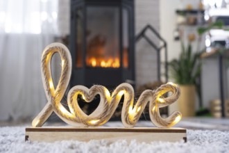 Valentine decor near fireplace stove with fire and firewood. Cozy home hearth in interior with