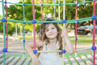Warm summer day. Adorable little girl with long blonde hair in a white dress. Attraction on the