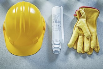 Building helmet protective gloves blueprints on concrete surface construction concept